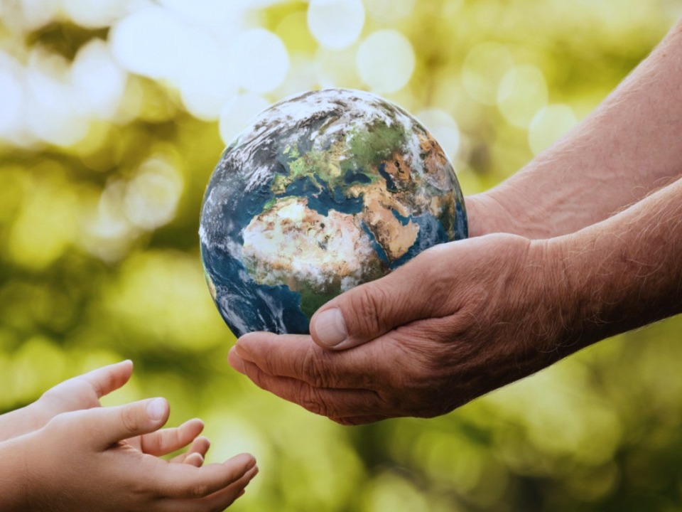 Hands passing a globe from one generation to another